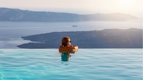 man relaxing in infinity swimming pool looking at the sea view picture id903400912